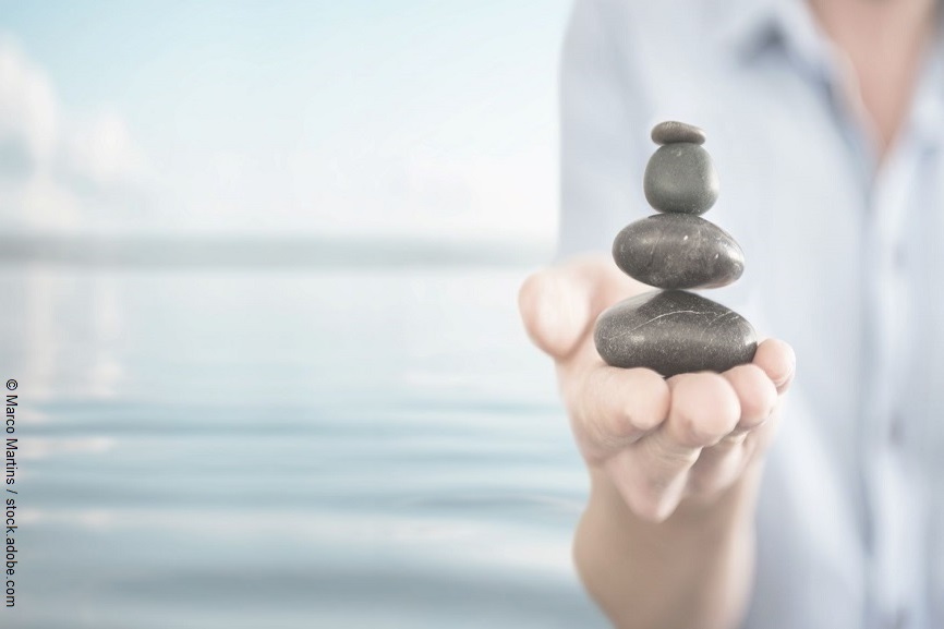 Eine Person hält eine Steinbalance Figur in der Hand.